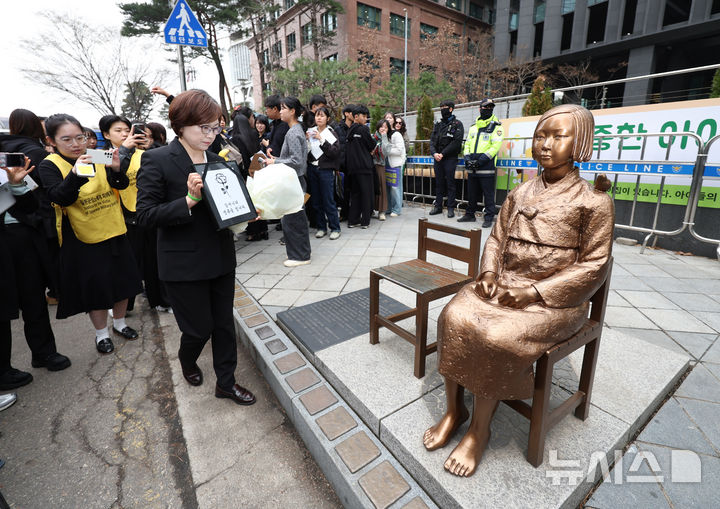 [서울=뉴시스] 김진아 기자 = 1일 서울 종로구 옛 주한 일본대사관 앞에서 열린 제1746차 일본군 성노예제 문제해결을 위한 정기 수요시위에서 이나영 정의연 이사장이 소녀상 옆 빈 의자에 피해자 영정을 올려두고 있다.&nbsp; 평화의 소녀상은 이날 수요시위에서 약 6년 만에 경찰 바리케이드를 벗어나 시민들 앞에 모습을 드러냈다. 안전 문제를 고려해 전면 철거 대신 한시 개방 방식을 택한 것으로 전해졌다. 경찰은 4월 말께 바리케이드 철거 여부를 다시 판단할 방침이다. 2026.04.01. bluesoda@newsis.com