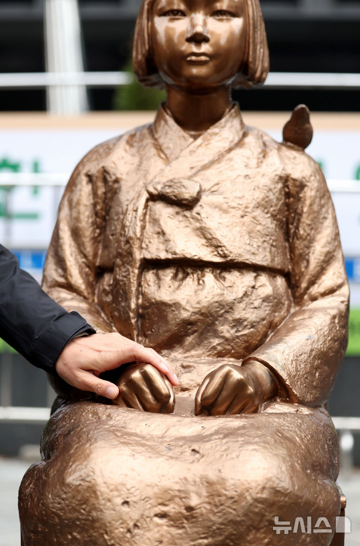 [서울=뉴시스] 김진아 기자 = 1일 서울 종로구 옛 주한 일본대사관 앞에서 열린 제1746차 일본군 성노예제 문제해결을 위한 정기 수요시위에서 한 시민이 소녀상의 손을 잡고 있다. 평화의 소녀상은 이날 수요시위에서 약 6년 만에 경찰 바리케이드를 벗어나 시민들 앞에 모습을 드러냈다. 안전 문제를 고려해 전면 철거 대신 한시 개방 방식을 택한 것으로 전해졌다. 경찰은 4월 말께 바리케이드 철거 여부를 다시 판단할 방침이다. 2026.04.01. bluesoda@newsis.com