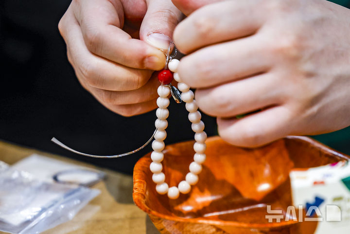 [서울=뉴시스] 정병혁 기자 = 2일 서울 강남구 코엑스에서 열린 2026서울국제불교박람회에서 참관객이 합장주를 만들고 있다. 2026.04.02. jhope@newsis.com