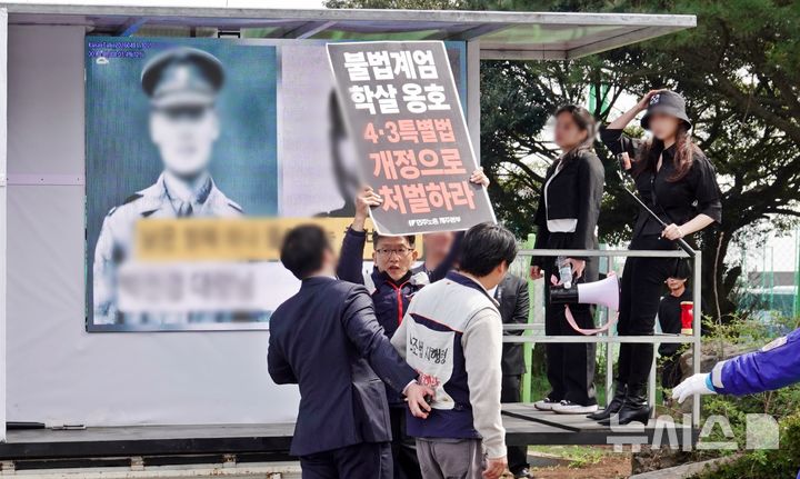 [제주=뉴시스] 임기환 전국민주노동조합총연맹 제주본부장이 3일 오전 제78주년 제주4·3 희생자 추념식이 열린 제주4·3평화공원 내 극우 단체 집회 현장에서 4·3 왜곡 처벌법 개정 촉구 팻말을 들고 있다가 경찰에 제지당하고 있다. 2026.04.03. oyj4343@newsis.com