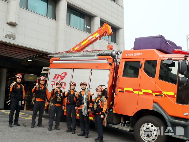 [군포=뉴시스] 길을 잃고 절벽 끝에 고립됐던 50대 등산객을 구조한 군포소방서 구조대원들이 상황을 마친 후 소방서 앞에서 기념 촬영을 하고 있다. (사진=군포소방서 제공).