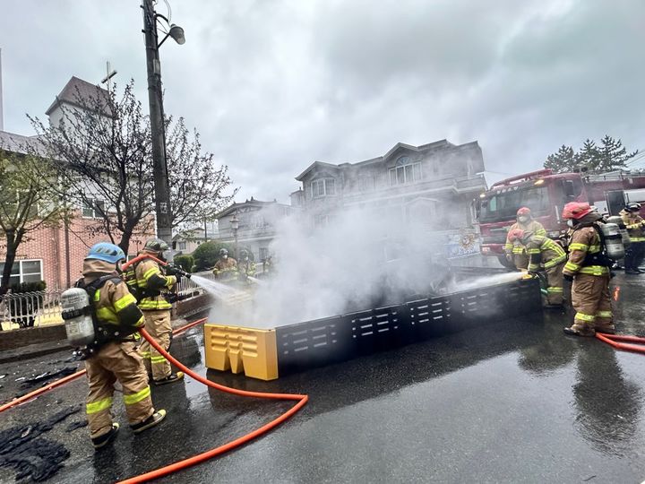 [창원=뉴시스]도로 연석 들이받은 전기차 택시에 '화재'가 나자 소방당국이 수조를 이용해 전기차를 냉각시키는 모습.(사진=창원소방본부 제공) 2026.04.04.photo@newsis.com *재판매 및 DB 금지