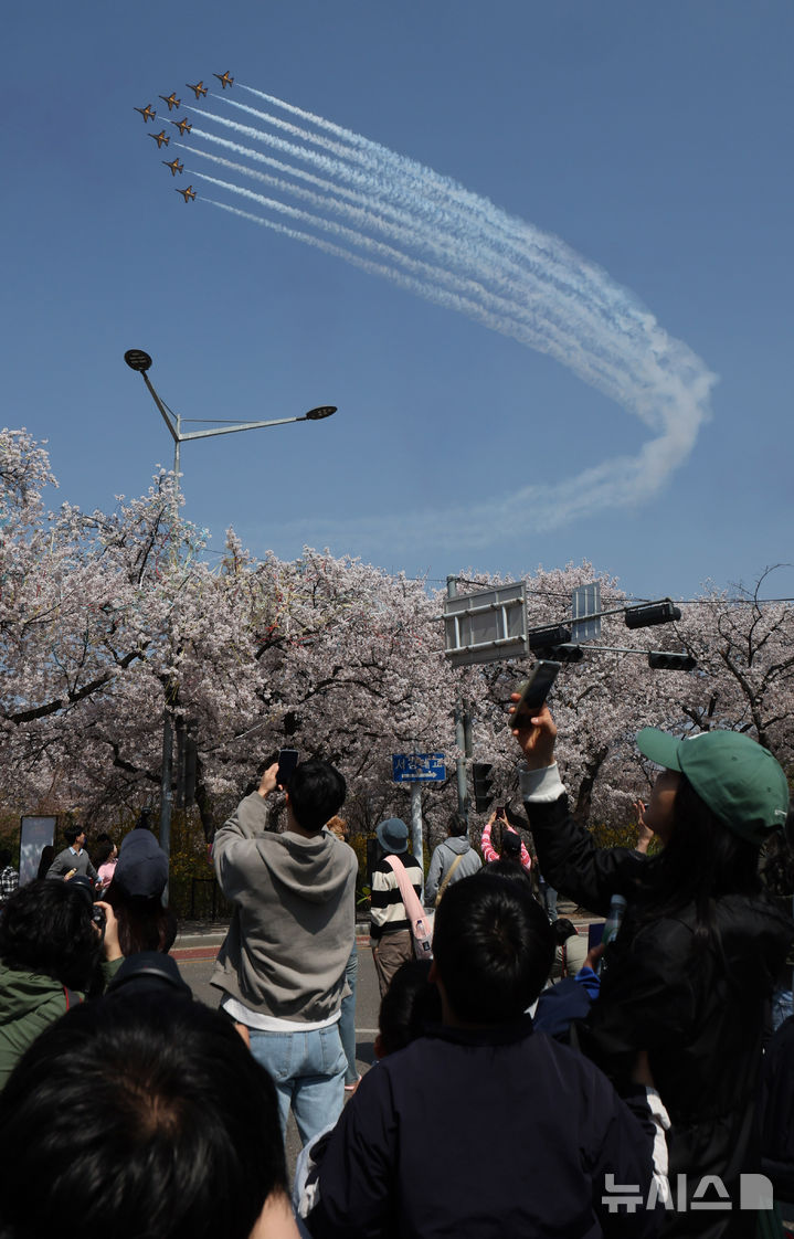 [서울=뉴시스] 배훈식 기자 = 2026 영등포 여의도 봄꽃축제가 열린 5일일 오후 서울 여의도 행사장을 찾은 시민들이 공군 특수 비행팀 '블랙이글스'의 축하 비행을 보고 있다. 2026.04.05. dahora83@newsis.com