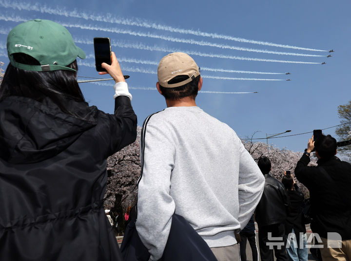 [서울=뉴시스] 배훈식 기자 = 2026 영등포 여의도 봄꽃축제가 열린 5일일 오후 서울 여의도 행사장을 찾은 시민들이 공군 특수 비행팀 '블랙이글스'의 축하 비행을 보고 있다. 2026.04.05. dahora83@newsis.com