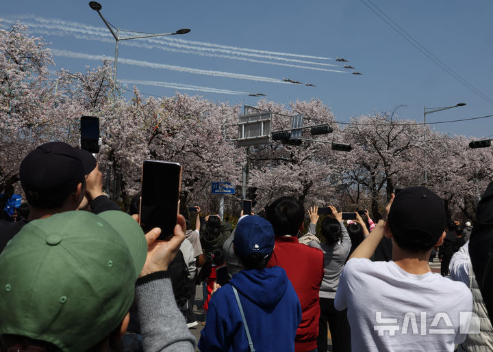 [서울=뉴시스] 배훈식 기자 = 2026 영등포 여의도 봄꽃축제가 열린 5일일 오후 서울 여의도 행사장을 찾은 시민들이 공군 특수 비행팀 '블랙이글스'의 축하 비행을 보고 있다. 2026.04.05. dahora83@newsis.com