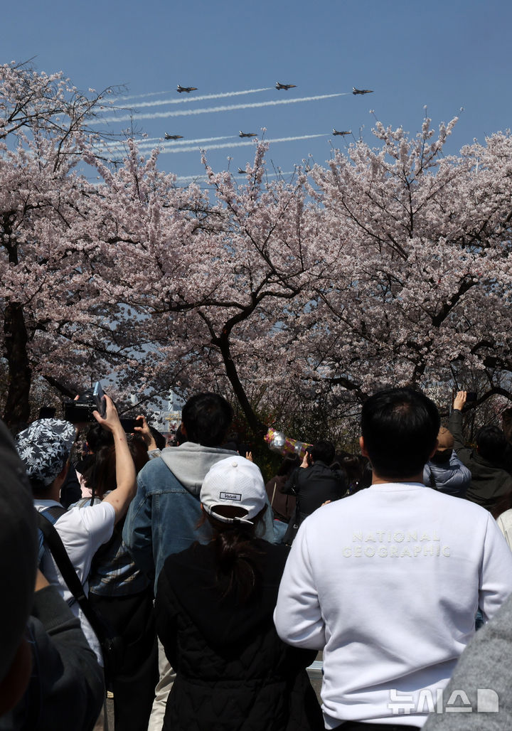 [서울=뉴시스] 배훈식 기자 = 2026 영등포 여의도 봄꽃축제가 열린 5일일 오후 서울 여의도 행사장을 찾은 시민들이 공군 특수 비행팀 '블랙이글스'의 축하 비행을 보고 있다. 2026.04.05. dahora83@newsis.com