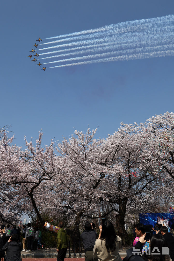 [서울=뉴시스] 배훈식 기자 = 2026 영등포 여의도 봄꽃축제가 열린 5일일 오후 서울 여의도 행사장을 찾은 시민들이 공군 특수 비행팀 '블랙이글스'의 축하 비행을 보고 있다. 2026.04.05. dahora83@newsis.com
