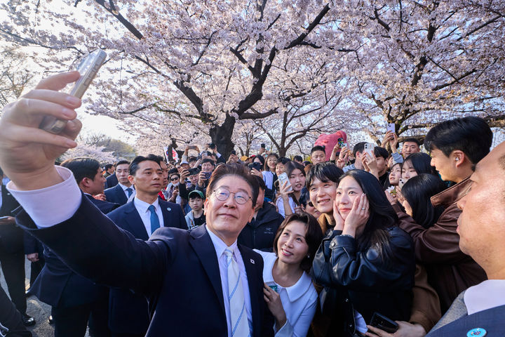 [서울=뉴시스] 이재명 대통령과 김혜경 여사가 5일 서울 여의도 윤중로에서 벚꽃을 배경으로 시민들과 기념촬영을 하고 있다. (사진=청와대 제공) 2026.04.05. photo@newsis.com *재판매 및 DB 금지