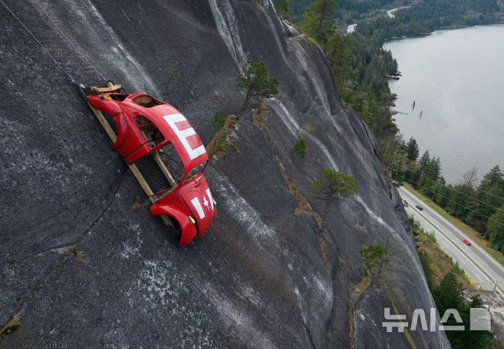 [스쿼미시=AP/뉴시스] 6일(현지 시간) 캐나다 브리티시컬럼비아(BC)주 스쿼미시의 씨투스카이 고속도로 위 절벽에 속이 비어 있는 폴크스바겐 비틀이 매달려 있다. 이에 대해 BC대학교 공대생이라고 주장하는 한 단체가 자신들의 소행이라고 밝히며, 이는 접근이 어려운 장소에 물체를 설치하는 전통 중 하나라고 주장했다. 주 공원 당국은 이에 대해 “심각한 공공 안전 위협”이라며 인기 암벽 등반 지역인 이곳을 폐쇄하고 철거할 것이라고 밝혔다. 2026.04.07.