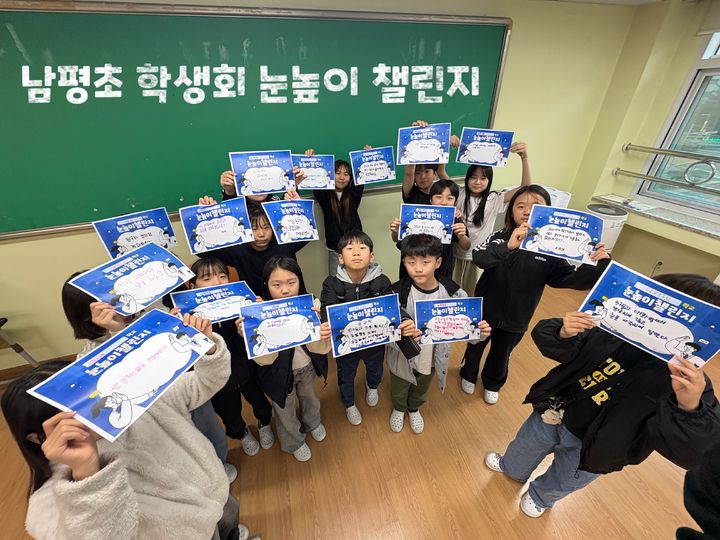 [청주=뉴시스] 충북 청주 남평초등학교 학생들이 눈높이 챌린지에 참여해 손 팻말을 들고 기념촬영을 하고 있다. (사진=충북도교육청 제공) 2026.04.07. photo@newsis.com    *재판매 및 DB 금지