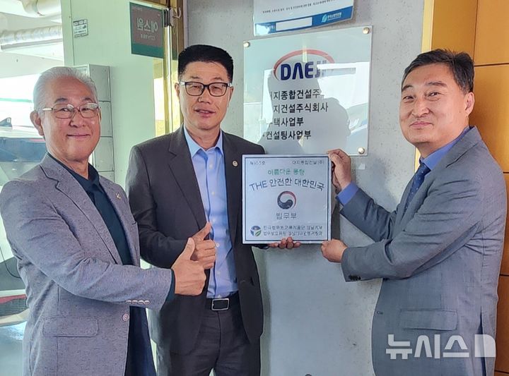 [창원=뉴시스]한국법무보호복지공단 박광흠(오른쪽) 경남지부장이 지난 7일 진주 대지종합건설㈜ 본사를 방문해 강동국(가운데) 회장에게 '아름다운 동행, THE 안전한 대한민국' 100호 현판을 전달하고 있다.(사진=한국법무보호복지공단 경남지부 제공) 2026.04.08. photo@newsis.com