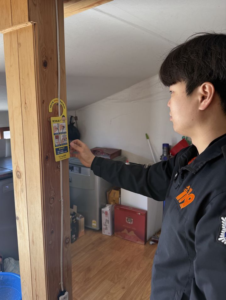 [영암=뉴시스] 홀몸어르신 가정에 문고리형 안전 점검 리스트 설치하는 영암소방서 대원. (사진=전남소방본부 제공) 2026.04.09. photo@newsis.com *재판매 및 DB 금지