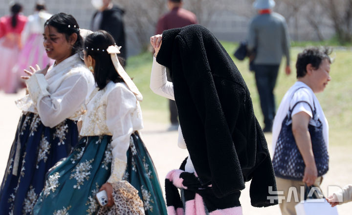 [서울=뉴시스] 추상철 기자 = 완연한 봄날씨를 보인 12일 오후 서울 종로구 경복궁에서 외국인관광객이 따가운 햇살에 자켓으로 머리를 가린 채 이동하고 있다. 2026.04.12. scchoo@newsis.com