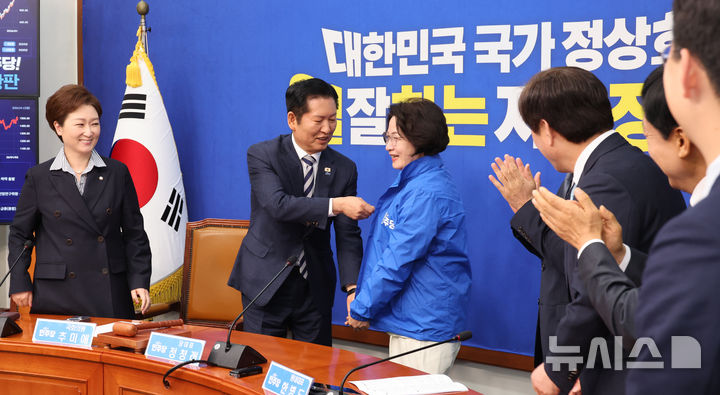 [서울=뉴시스] 김금보 기자 = 추미애 더불어민주당 경기도지사 후보가 13일 오전 서울 여의도 국회에서 열린 환영식에서 정청래 더불어민주당 대표로 부터 당 점퍼를 받아 입고 있다. 2026.04.13.kgb@newsis.com