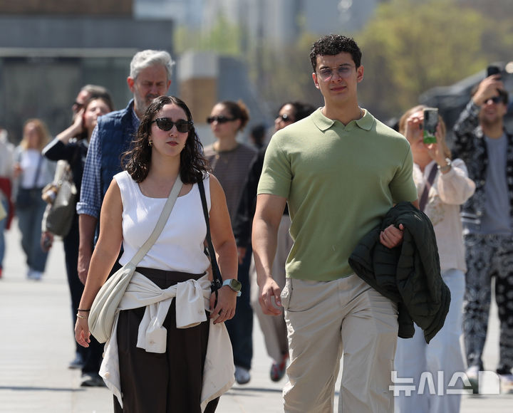 [서울=뉴시스] 조수정 기자 = 서울 낮 최고기온이 25도까지 오르며 초여름 날씨를 보인 13일 서울 종로구 광화문광장에서 한 경찰이 겉옷을 벗어 들고 걸어가고 있다. 2026.04.13. chocrystal@newsis.com