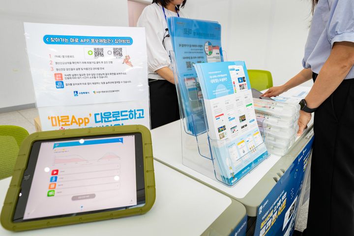 [수원=뉴시스] 수원시 정신건강 자가관리 앱 '마로' 홍보 부스에서 시민들이 앱 다운로드와 사용 방법을 안내받고 있다. (사진=수원시 제공) 2026.04.14. photo@newsis.com *재판매 및 DB 금지