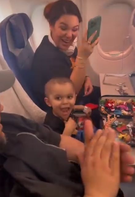 [서울=뉴시스] 희귀 암을 극복한 크루즈가 집으로 돌아가는 비행기 안에서 승객과 승무원들로부터 응원을 받고 웃고 있다. (사진=사우스웨스트 항공 페이스북 캡처) 2026.04.14.