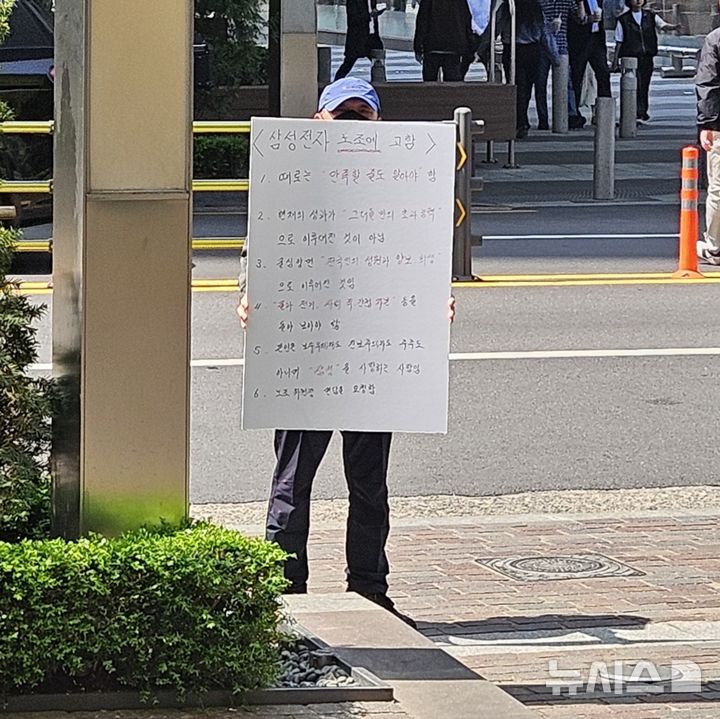[서울=뉴시스]남주현 기자=15일 삼성전자 서초사옥 앞에서 한 시민이 노조의 과도한 성과급 요구를 비판하는 내용의 피켓을 들고 1인 시위에 나서고 있다. 2026.04.15.njh32@newsis.com