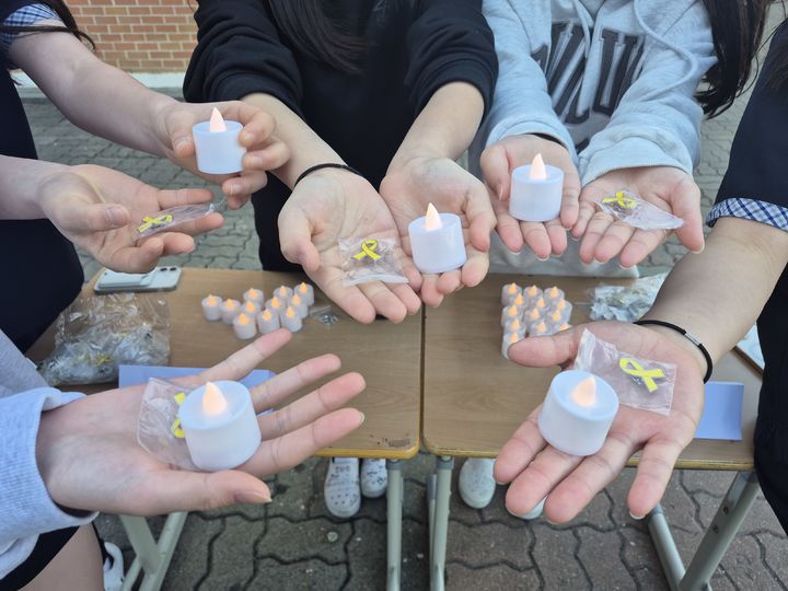 [안산=뉴시스] 안산 초지중학교 학생들이 세월호 리본 뱃지와 촛불을 들고 기념촬영을 하고 있다. (사진=안산교육지원청 제공) 2026.04.16. photo@newsis.com *재판매 및 DB 금지