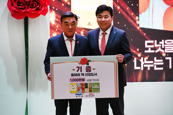 [울산=뉴시스] 16일 울산도서관에서 황재철 BNK경남은행 부행장이 김두겸 울산시장에게 올해의 책 기증서를 전달하고 있다. (사진=BNK경남은행 제공) 2026.04.16. photo@newsis.com *재판매 및 DB 금지