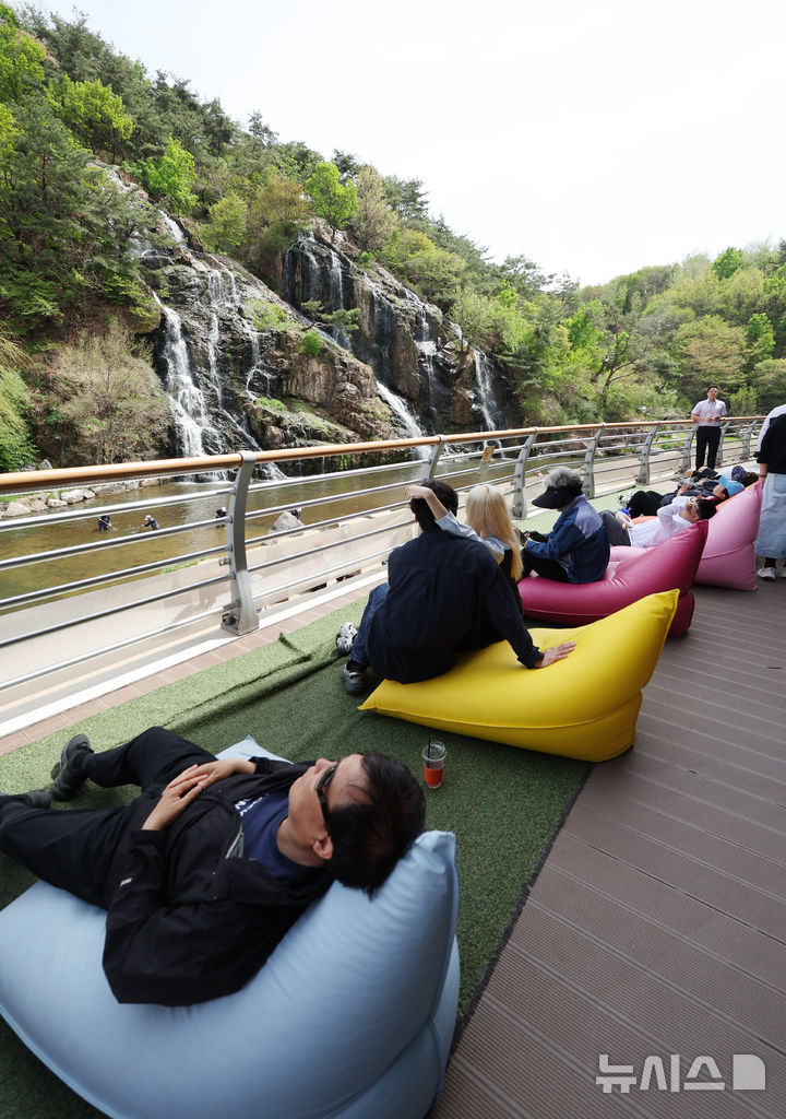[서울=뉴시스] 김진아 기자 = 낮 최고기온이 28까지 오르는 등 초여름 날씨를 보인 16일 서울 서대문구 홍제천 인공폭포를 찾은 시민들이 폭포를 바라보며 더위를 식히고 있다. 2026.04.16. bluesoda@newsis.com