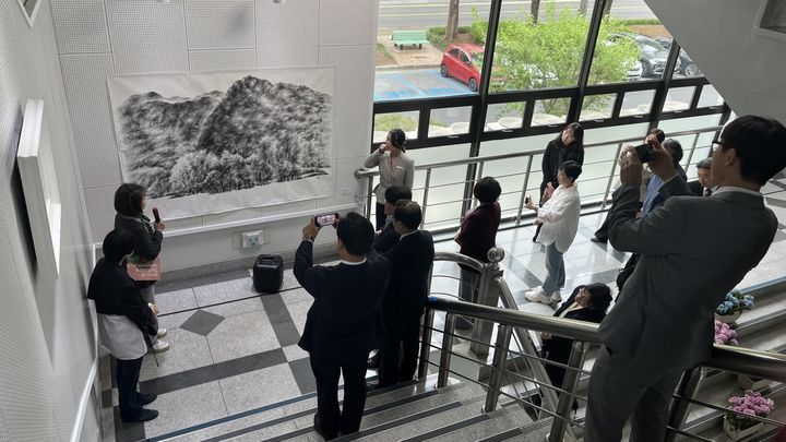 [밀양=뉴시스] 밀양시청 갤러리 전시 개막 행사 중, 참석자들이 작품 앞에 모여 작가의 설명을 경청하고 있다. (사진=밀양시 제공) 2026.04.17. photo@newsis.com *재판매 및 DB 금지