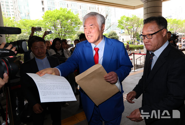 [서울=뉴시스] 황준선 기자 = 서울서부지방법원 난동 사건의 배후 의혹을 받아 재판에 넘겨진 전광훈 사랑제일교회 목사가 17일 서울 마포구 서울서부지방법원에서 열린 2차 공판을 마친 뒤 법원을 나서며 취재진에게 소명 자료를 건네고 있다. 2026.04.17. hwang@newsis.com