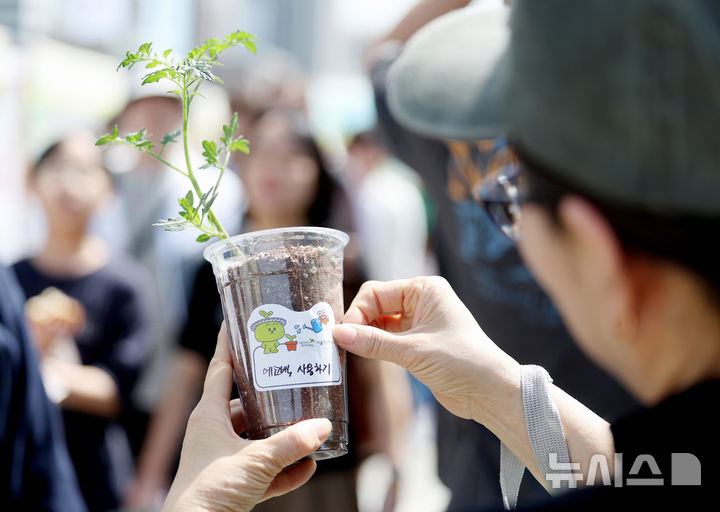 [서울=뉴시스] 김진아 기자 = 지구의 날(매년 4월 22일)을 맞아 18일 서울 종로구 광화문광장에서 폐기물 감량을 주제로 열린 '2026 지구의 날 기념행사'에서 한 시민이 토마토 모종에 지구를 아끼기 위한 실천메시지를 적은 스티커를 붙이고 있다. 2026.04.18. bluesoda@newsis.com