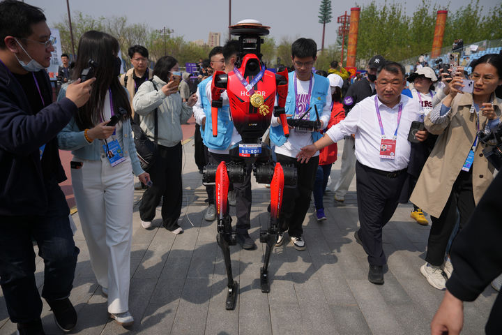 The winner of the humanoid robot half-marathon from Honor is chased by journalists after a press conference at the Beijing E-Town Half Marathon and Humanoid Robot Half-Marathon on the outskirts of Beijing, Sunday, April. 19, 2026. (AP Photo/Andy Wong)