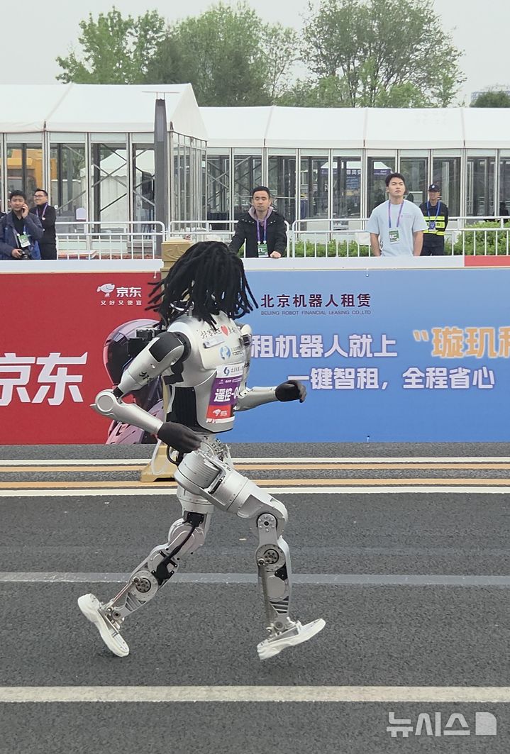 [베이징=뉴시스]박정규 특파원 = 19일 중국 베이징 이좡에서 열린 하프마라톤에서 레게 스타일의 머리카락을 얹은 채 대회에 참가한 휴머노이드 로봇이 출발해 달리고 있다. 2026.04.19. pjk76@newsis.com