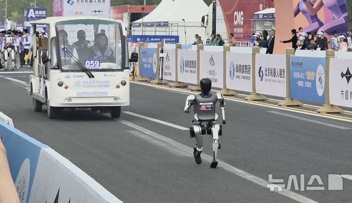 [베이징=뉴시스]박정규 특파원 = 19일 중국 베이징 이좡에서 열린 하프마라톤에서 대회에 참가한 휴머노이드 로봇이 원격으로 제어하는 차량과 함께 트랙을 달리고 있다. 2026.04.19. pjk76@newsis.com