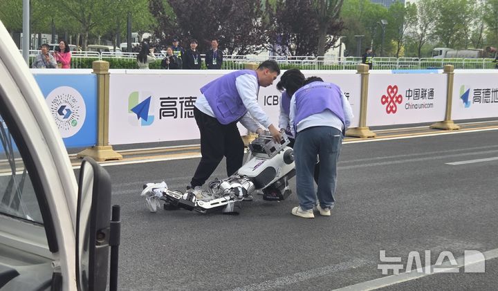 [베이징=뉴시스]박정규 특파원 = 19일 중국 베이징 이좡에서 열린 하프마라톤에서 대회에 참가한 휴머노이드 로봇이 출발지점에서 달리다 넘어져 관계자들이 로봇을 들어올리고 있다. 2026.04.19. pjk76@newsis.com