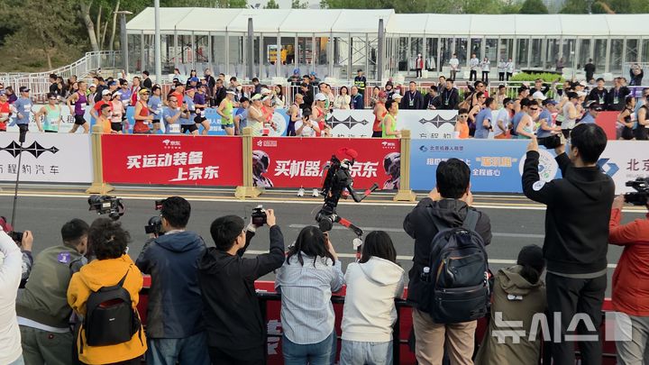 [베이징=뉴시스]박정규 특파원 = 19일 중국 베이징 이좡에서 열린 하프마라톤에 참가한 휴머노이드 로봇이 대회가 시작되자 대회 참가자들 옆에서 질주하고 있다. 2026.04.19. pjk76@newsis.com
