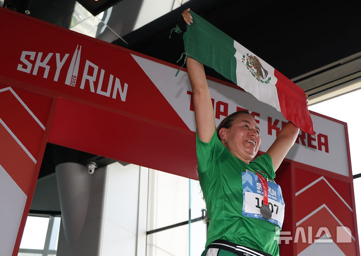 [서울=뉴시스] 배훈식 기자 = 19일 오전 서울 송파구 롯데월드타워에서 열린 수직 마라톤 대회 '2026 롯데월드타워 스카이런' 행사에서 한 참가자가 멕시코 국기를 들고 기념 촬영을 하고 있다. (공동취재) 2026.04.19. photo@newsis.com