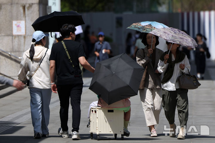 [서울=뉴시스] 김선웅 기자 = 서울 낮 최고기온이 29도를 기록하며 초여름 날씨를 보인 19일 서울 종로구 광화문광장에서 시민들이 양산으로 햇볕을 가리며 길을 걷고 있다. 2026.04.19. mangusta@newsis.com