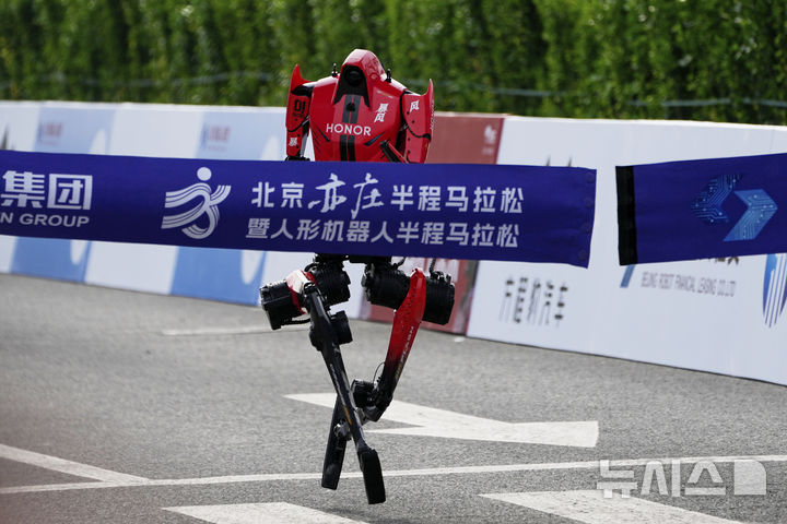 [베이징=AP/뉴시스] 19일(현지시간) 베이징 이좡(E-Town)에서 열린 '제2회 휴머노이드 로봇 하프마라톤 대회'에서 아너(Honor)사의 휴머노이드 로봇 '샨뎬'이 결승선을 통과하고 있다. 2026.04.19.
