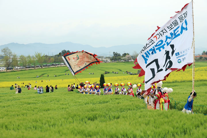 [고창=뉴시스] 지난 18일 고창군 공음면 학원농장에서 제23회 청보리밭축제가 개막했다. 고창청보리밭축제 상징깃발을 든 기접놀이패와 농악단이 보리밭 사잇길을 지나고 있다. *재판매 및 DB 금지