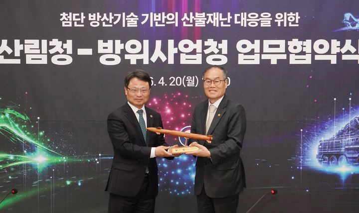 [대전=뉴시스] 박은식 산림청장(왼쪽)이 20일 산림항공본부에서 방위사업청과 첨단 방산기술을 활용한 산불재난 대응 체계 강화를 위한 업무협약을 체결한 뒤 산불피해목으로 만든 천궁-2 모형을 이용철 방위사업청장에 선물하고 있다.(사진=산림청 제공) *재판매 및 DB 금지