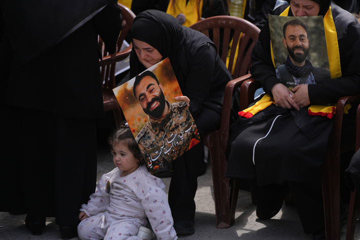 [크파르 시르( 레바논)=AP/뉴시스] 레바논의 헤즈볼라 전사자 합동 장례식이 열린 4월 21일 크파르 시르 시내의 장례식장에서 유족들이 안고 있는 고인들의 활짝 웃고 있는 사진과 무심한 아기의 모습이 묘한 대조를 이룬다. 2026. 04. 22. 