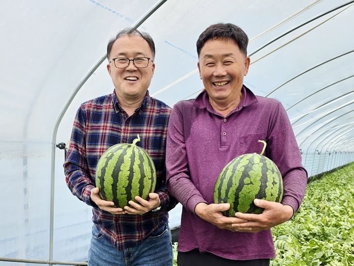 충남 부여 조성술 달인 수박 산지에서 임선기(왼쪽) 선별 달인, 조성술 재배 달인이 수박을 들고 웃고 있다. (사진=이랜드 제공) *재판매 및 DB 금지