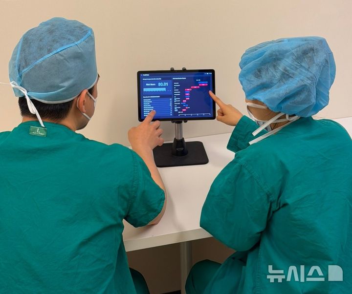 [서울=뉴시스] 의료진이 수술 전 전자의무기록(EMR)을 바탕으로 환자의 수술 후 중증 이벤트인 사망 위험을 예측하는 AI 기술이 적용된 'PreOPRisk'를 테스트하고 있는 모습. (사진= 서울아산병원 제공)