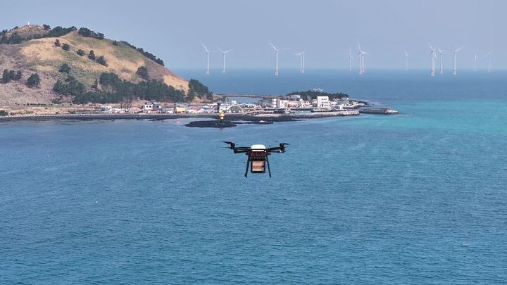 [서울=뉴시스]우주항공청이 한국전자통신연구원과 함께 드론과 배송 협업 로봇, 도킹스테이션을 결합한 ‘드론-로봇 협업 문 앞 배송 체계’ 실증 사업을 진행했다. 비양도에서 출발한 드론이 금능포구로 향하는 모습. (사진=우주청 제공) *재판매 및 DB 금지