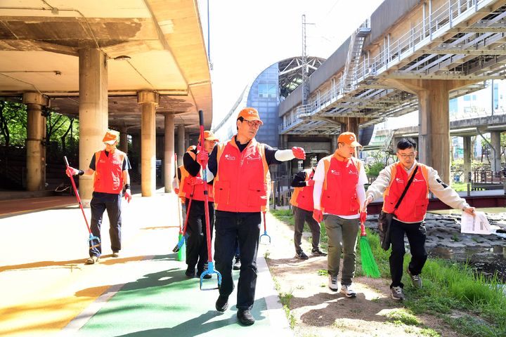 [서울=뉴시스] 김성수 SK브로드밴드 사장(앞 줄 중앙) 등 임직원들이 24일 도림천 일대에서 환경 정화 및 생태계 복원을 위한 자원 봉사 활동을 진행했다. (사진=SKB 제공) *재판매 및 DB 금지