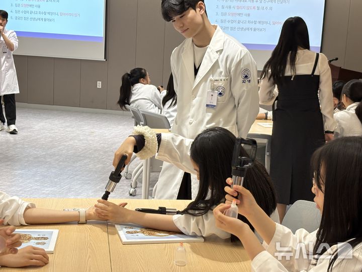 [서울=뉴시스] 대치중학교 학생들이 한의사 가운을 입고 직접 부항 치료를 시술하고 있다. (사진= 자생한방병원 제공)