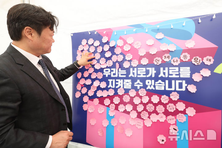 [서울=뉴시스] 조수정 기자 = 한국자살예방협회 백종우 협회장이 24일 오전 서울 종로구 청계광장에 마련된 한국자살예방협회 '천명지킴 발대식' 부스에서 응원 문구를 작성해 붙이고 있다. 2026.04.24. chocrystal@newsis.com