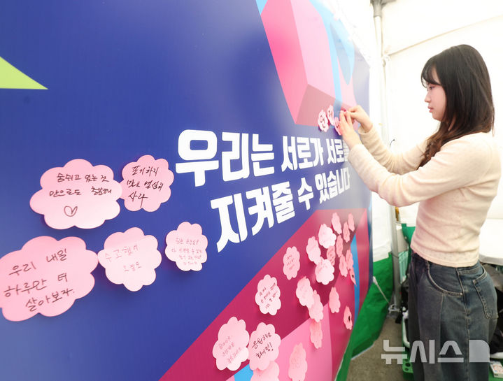 [서울=뉴시스] 조수정 기자 = 24일 오전 서울 종로구 청계광장에 마련된 한국자살예방협회 '천명지킴 발대식' 부스에서 시민이 응원 문구를 작성해 붙이고 있다. 2026.04.24. chocrystal@newsis.com