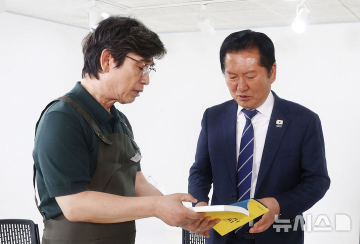 [서울=뉴시스] 김혜진 기자 = 정청래 더불어민주당 대표가 24일 오후 서울 성동구 언더스탠드에비뉴에 마련된 청각장애인 수제화 브랜드 '아지오' 매장 오픈 행사에 참석해 유시민 작가로부터 '사랑이 있으니 살아집디다' 책을 전달 받고 있다. (공동취재) 2026.04.24. photo@newsis.com