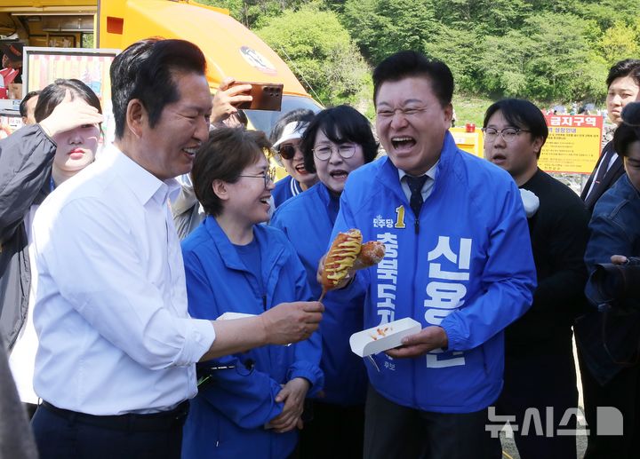 [진천=뉴시스] 서주영 기자 = 정청래 더불어민주당 대표가 25일 오후 충북 진천군 농다리 축제장을 방문해 신용한 충북지사 예비후보와 함께 핫도그를 먹고 있다. 2026.04.25. juyeong@newsis.com 