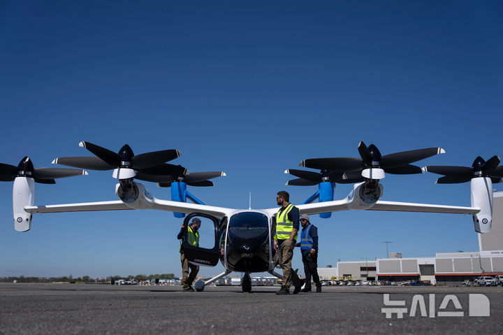 [뉴욕=AP/뉴시스] 27일(현지 시간) 미국 뉴욕 존 F. 케네디 국제공항에서 공항 관계자들이 '조비 에비에이션'의 전기 수직이착륙기(eVTOL) 이륙을 준비하고 있다. 조비 에비에이션은 '하늘을 나는 택시'로 불리는 eVTOL의 실제 비행경로와 환경에서의 운항을 검증하는, 열흘간의 시범 비행에 나섰다. 2026.04.28.