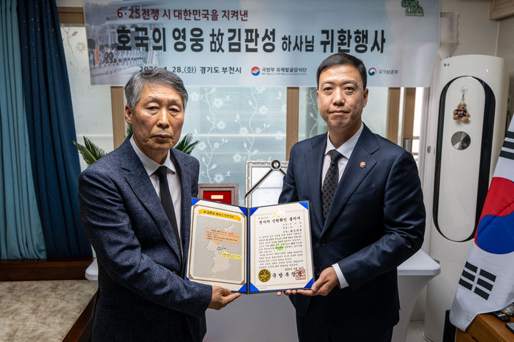 [서울=뉴시스] 28일 오전에 열린 故 김판성 하사 호국의 영웅 귀환 행사에서 김성환 국방부 유해발굴감식단장 직무대리(육군 중령, 오른쪽)가 유가족 대표인 고 김판성 하사의 친조카 김창선 씨(왼쪽)에게 전사자 신원확인 통지서를 전달하고 있다. (사진=국방부 제공) 2026.04.28. photo@newsis.com&nbsp; *재판매 및 DB 금지